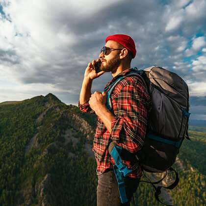 Man uses mobile phone while hiking in wilderness mountains