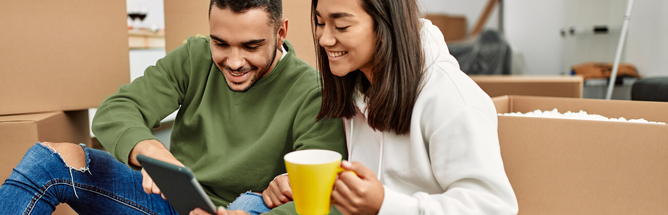 a couple looking at their tablet while packing their apartment