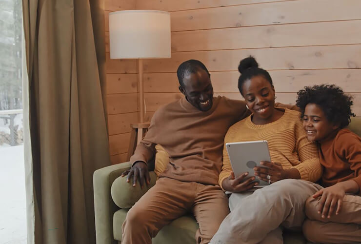 Family watching shows on their tablet, cozy together in a wintery cabin.